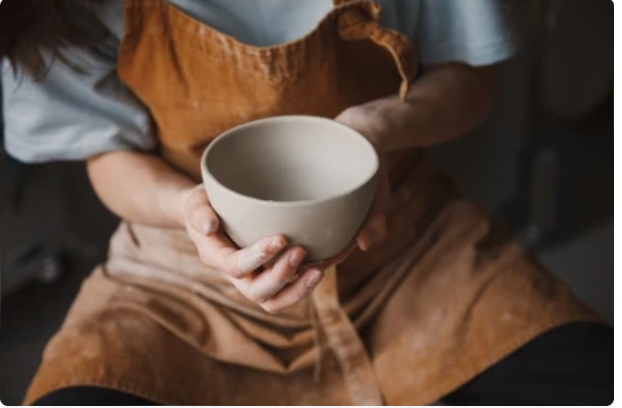 teenager shaping clay on pottery wheel during after-school pottery class