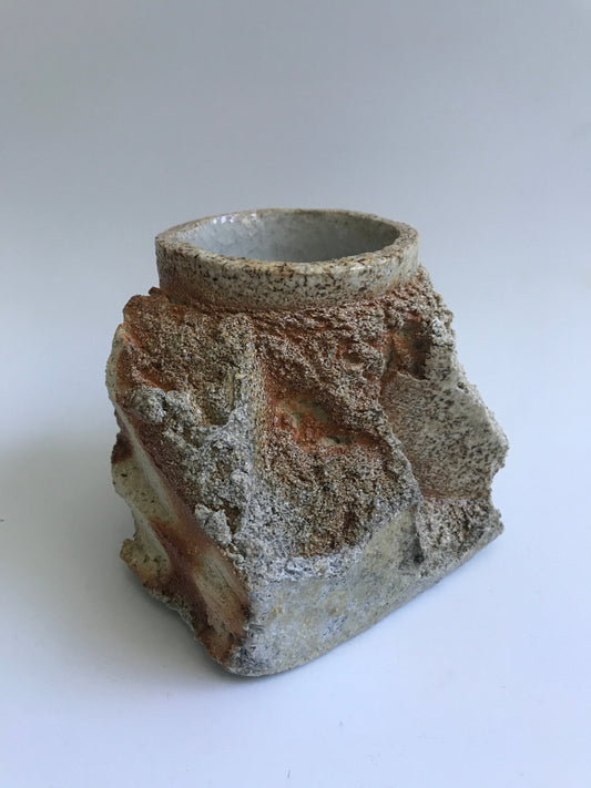Rocklike surface on one side and a cup on the other side.