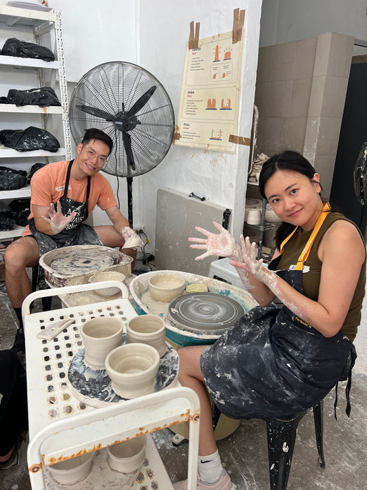 A couple sitting at wheels date night pottery wheel throwing class