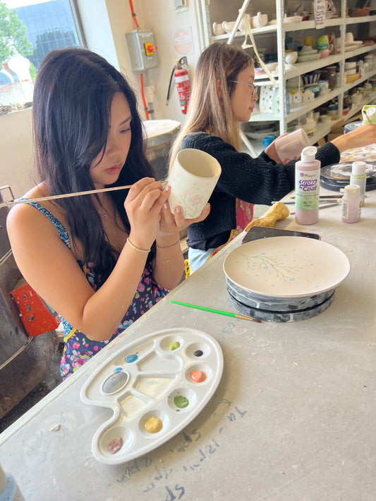 People painting on ceramic pieces, glazing