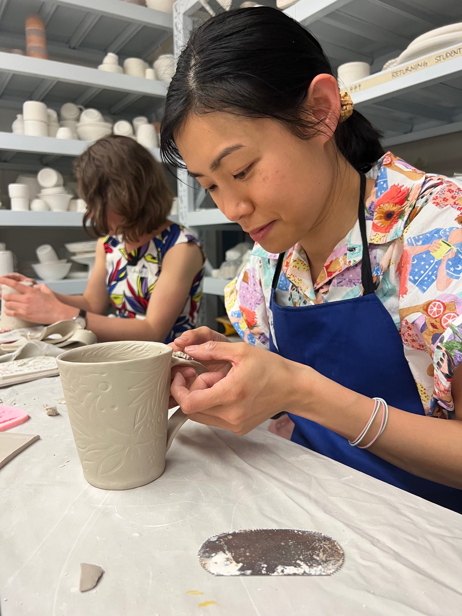 Woman hand building a mug, attaching a handle